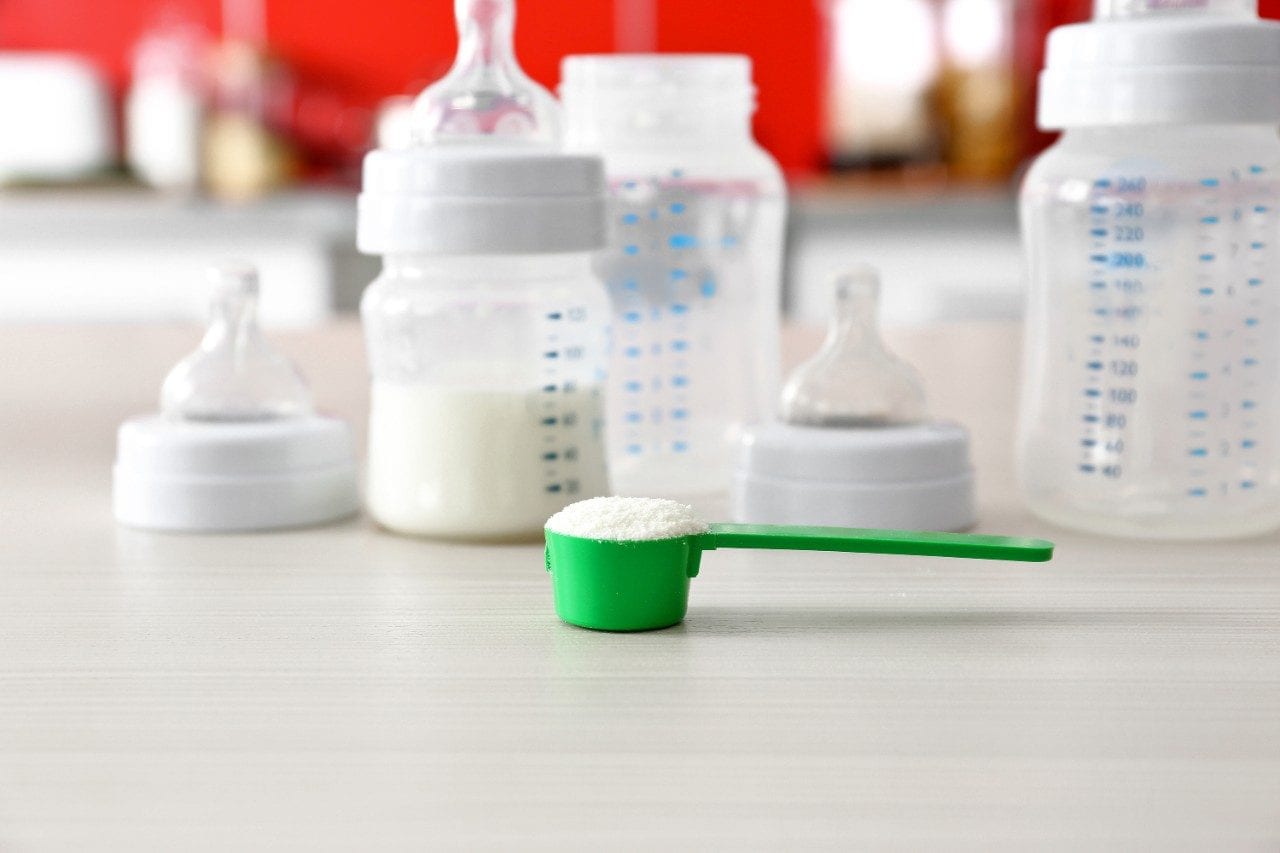 Feeding bottles and baby milk formula on kitchen background