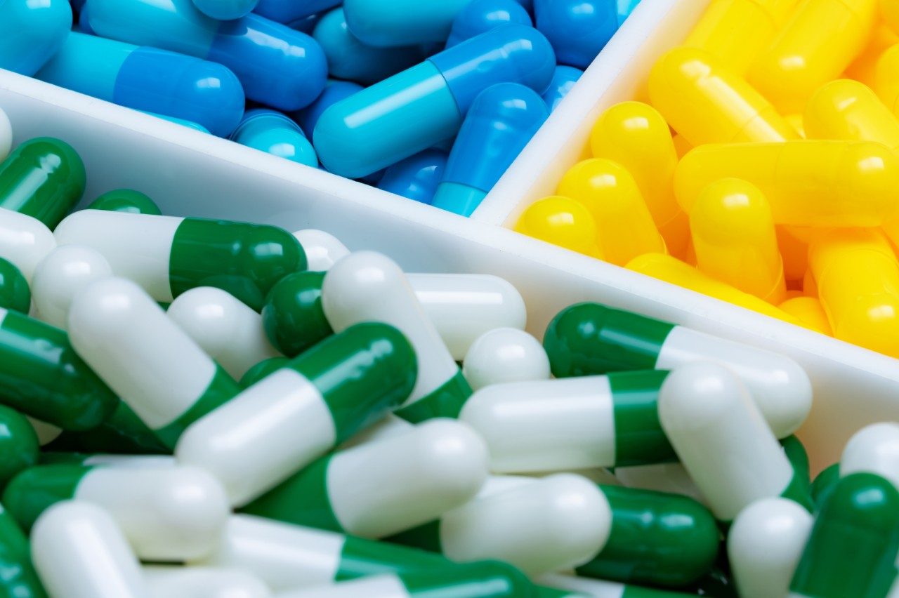 Blue, yellow, and green-white capsules pills in plastic tray