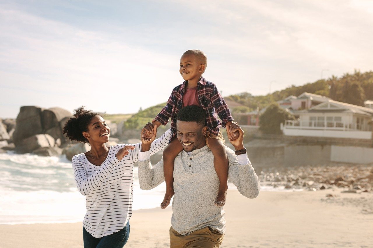 Happy black family walking on the beach on a sunny day